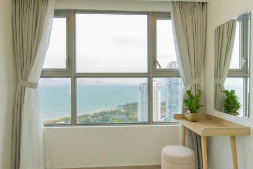 a room with large windows and a table with a plant at Monica Homestay - Căn hộ The Song Vũng Tàu in Vung Tau