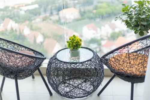 three chairs and a glass table with a plant in a window at Monica Homestay - Căn hộ The Song Vũng Tàu in Vung Tau