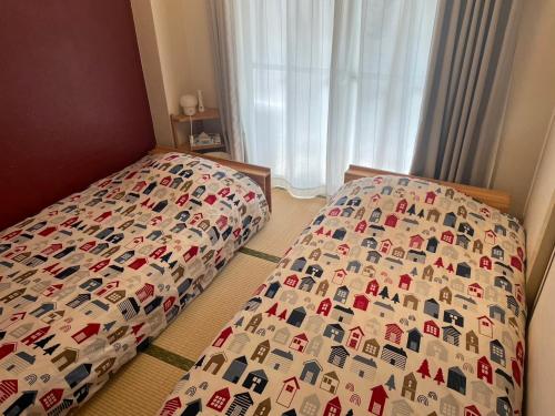 a bed with a comforter on it in a bedroom at Fukuoka Condominium in Fukuoka