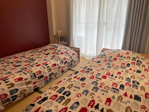 a bedroom with two twin beds with a bedspread with cars on it at Fukuoka Condominium in Fukuoka
