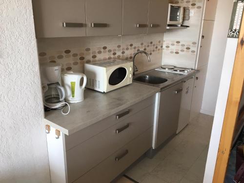 une petite cuisine avec un micro-ondes et un évier dans l'établissement Studio avec loggia à Super Besse, proche des pistes - FR-1-814-112, à Besse-et-Saint-Anastaise