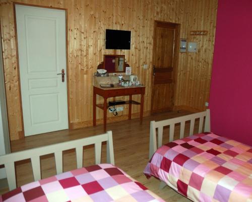 a bedroom with two beds and a desk and a tv at L'Horizon des Landes in Doazit