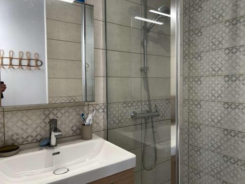 La salle de bains est pourvue d'une douche et d'un lavabo blanc. dans l'établissement Appartement T2 avec Cabine, Terrasse et Climatisation à Saint Pierre la Mer - FR-1-229D-156, à Fleury