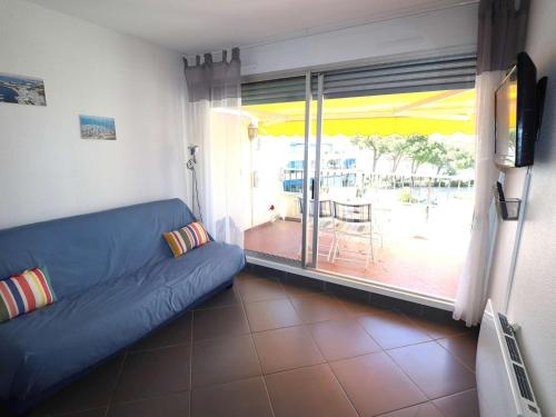 un salon avec un canapé bleu et un balcon dans l'établissement Studio ensoleillé à Port Camargue avec terrasse et parking - FR-1-307-283, au Grau-du-Roi