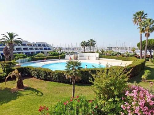 - une piscine bordée de palmiers et un complexe dans l'établissement Studio ensoleillé à Port Camargue avec terrasse et parking - FR-1-307-283, au Grau-du-Roi