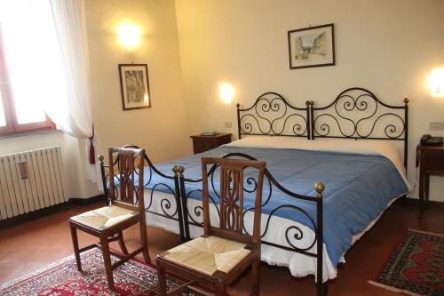 a bedroom with a large bed with two chairs at B&B L'Agnolo Di Caroti Cinzia in Montepulciano