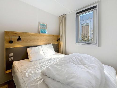 - un lit blanc dans une chambre avec fenêtre dans l'établissement Mobil-home Grand Confort à 200m plage, camping avec piscine, terrasse, WiFi inclus - 4 pers. - FR-1-361A-37, à Jullouville