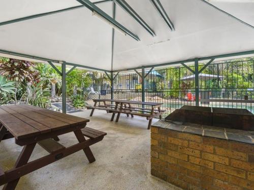 a picnic table and benches under a tent at Jacaranda Villa Korora Beach NSW in Kororo Basin