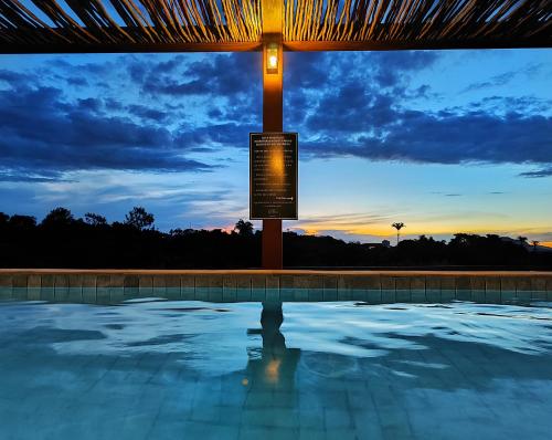 a swimming pool with a sunset in the background at Resort QSB - Um novo padrão de conforto e lazer no coração da cidade in Pirenópolis