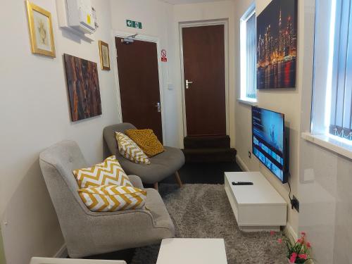 a living room with two chairs and a flat screen tv at Private 1 Bed Flat Near The Aston Villa Park in Birmingham