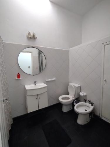 ein Badezimmer mit Toilette, Waschbecken und Spiegel in der Unterkunft CASA PARA 4 PERSONAS, con asador y cochera in Cordoba