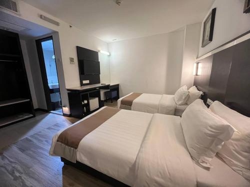 a hotel room with two beds and a flat screen tv at Dreamtel Kota Kinabalu in Kota Kinabalu
