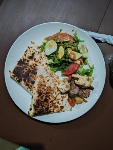 a white plate of food with a salad and pizza at Ana Paraíso entre Arboles in Drake