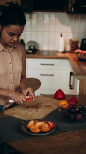 a woman cutting tomatoes on a cutting board in a kitchen at tbarn - Будинок з чаном в Карпатах - tranquilo barn in Starunya