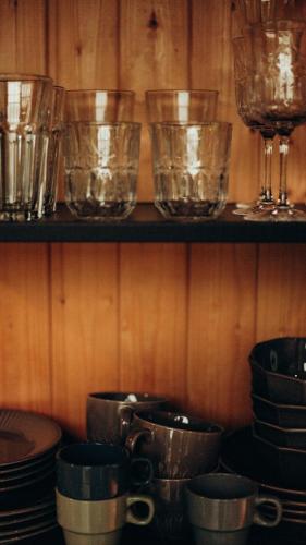 a shelf with bowls and glasses on a wooden wall at tbarn - Будинок з чаном в Карпатах - tranquilo barn in Starunya