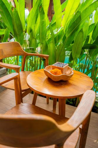 a wooden table with a bowl of food on it at Cempaka Kembar Ubud in Ubud