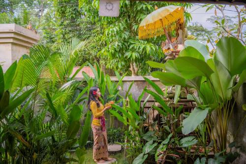 a woman standing in a garden with an umbrella at Cempaka Kembar Ubud in Ubud