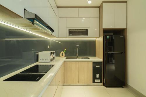 a kitchen with a black refrigerator and a sink at Ly's Homestay - Nera Garden Huế in Thôn Văn Dương
