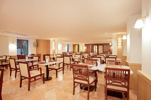 a restaurant with tables and chairs in a room at Jomtien Thani Hotel in Jomtien Beach