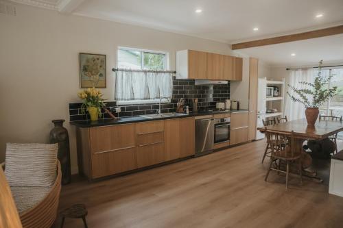 a kitchen with wooden cabinets and a table and a dining room at Harker House in Healesville