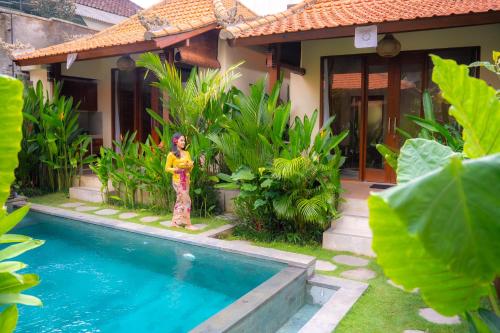 a person standing in front of a house with a swimming pool at Cempaka Kembar Ubud in Ubud