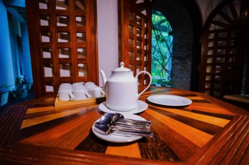 a wooden table with a tea kettle and plates on it at Kandahena Mansion in Akuressa