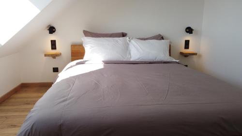 a bed with white sheets and pillows in a room at Appart Côte d'Opale in Condette
