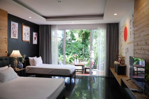 a hotel room with two beds and a window at Eat n Sleep in Phuket