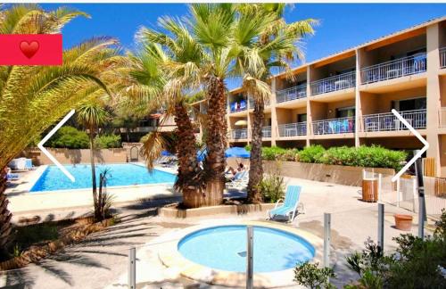 un complexe avec une piscine, des palmiers et un bâtiment dans l'établissement Le Marina, à Sanary-sur-Mer