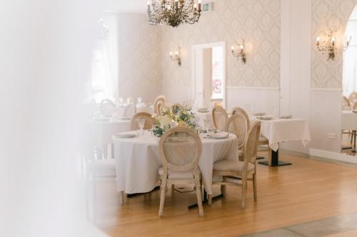 a dining room with white tables and chairs and a chandelier at Hôtel Château Schengen in Schengen