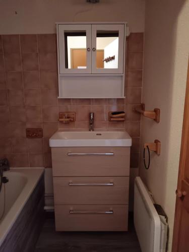 a bathroom with a sink and a mirror and a tub at Appartement confortable avec vue sur la montagne in Notre-Dame-de-Bellecombe