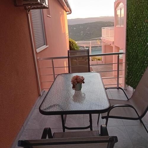 a table on a balcony with a vase of flowers on it at Apartmani Žuti in Neum