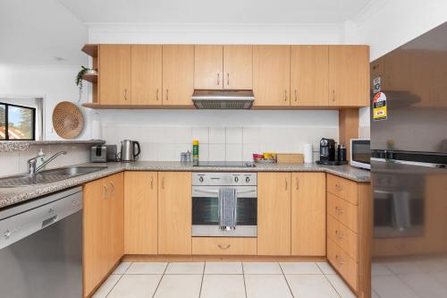 a kitchen with wooden cabinets and a stove at The Petal & Pod - A Sepal Stay in Perth