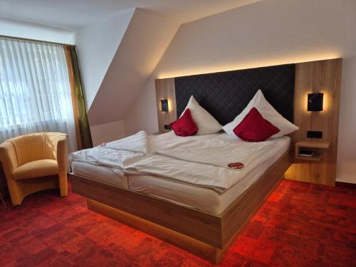 a bedroom with a large bed with red pillows at Hotel St. Georg Garni in Celle