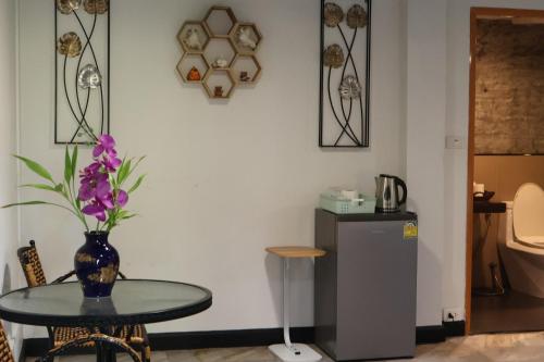 a table with a vase of flowers and a refrigerator at Eat n Sleep in Phuket Town