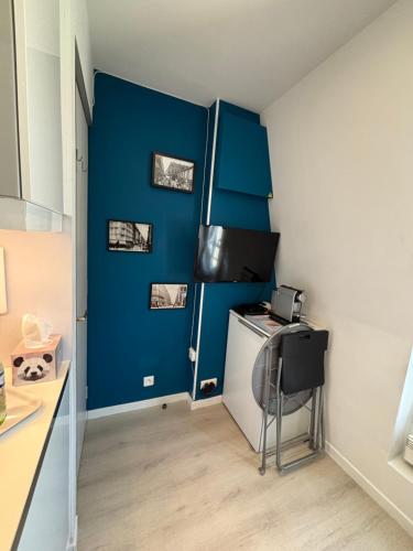 d'une cuisine avec des murs bleus, un bureau et une chaise. dans l'établissement Paris 17 - Coeur Batignolles - Beau studio 10 m2 -110 sqf - Etat neuf - Calme - Idéal une personne - single occupancy, à Paris