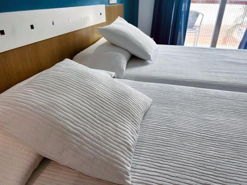 two beds with white sheets and pillows next to a window at La Cabaña in Peñíscola