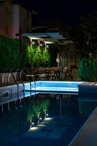 a swimming pool at night with tables and chairs at Sea house Afrodita1-rooms in Nesebar