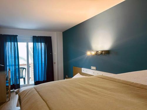 a bedroom with a bed with blue walls and a window at La Cabaña in Peñíscola