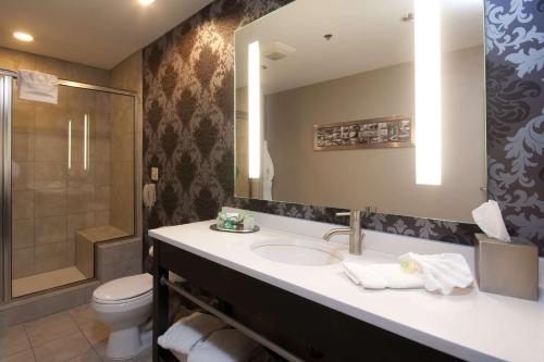 a bathroom with a sink and a toilet and a mirror at The Giacomo, an Ascend Collection Hotel in Niagara Falls