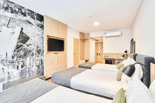 a hotel room with two beds and a flat screen tv at Dazzler by Wyndham Rosario in Rosario