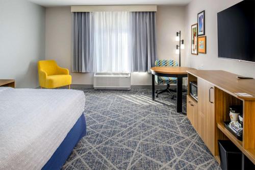 a hotel room with a bed and a desk and a television at Hampton Inn By Hilton St Louis Airport in Saint Louis