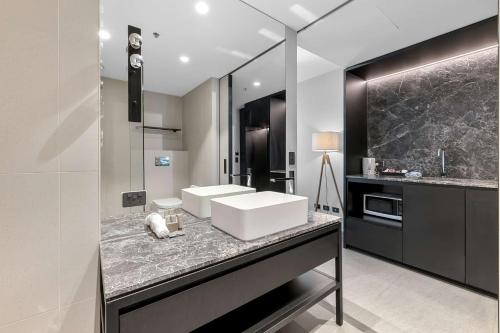 メルボルンにあるClarion Apartments South Melbourneのバスルーム(大理石のカウンターに白いシンク付)
