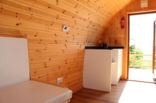 a kitchen with wooden walls and a white refrigerator at Bowdens Crest Glamping Pods -Adults Only in Aller
