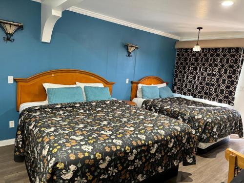 two beds in a room with blue walls at El Dorado Motel in Gardena