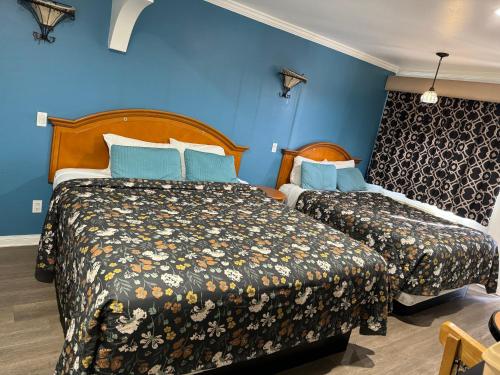 two beds in a room with blue walls at El Dorado Motel in Gardena