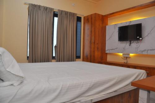 a bedroom with a bed with a tv on the wall at Hotel Shivar in Kalam