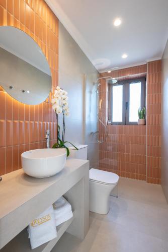 a bathroom with a sink and a toilet and a mirror at Alysos Luxurious Apartments in Mirina