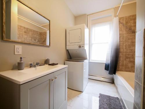 a bathroom with a sink and a washer at Serene Two-Bedroom Retreat - close to NYC in Jersey City