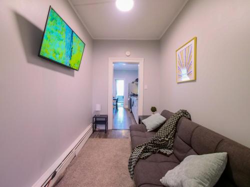 a living room with a couch and a tv on the wall at Serene Two-Bedroom Retreat - close to NYC in Jersey City